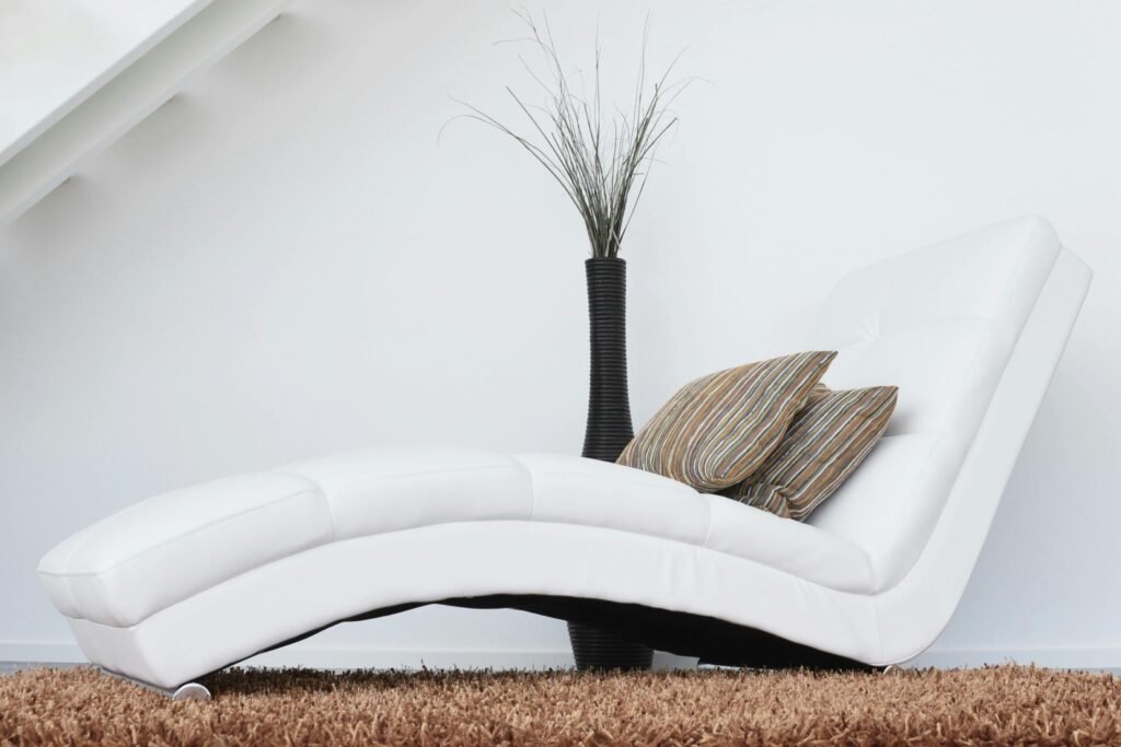 Elegant white lounge chair with cushions on plush carpet, perfect for relaxation.