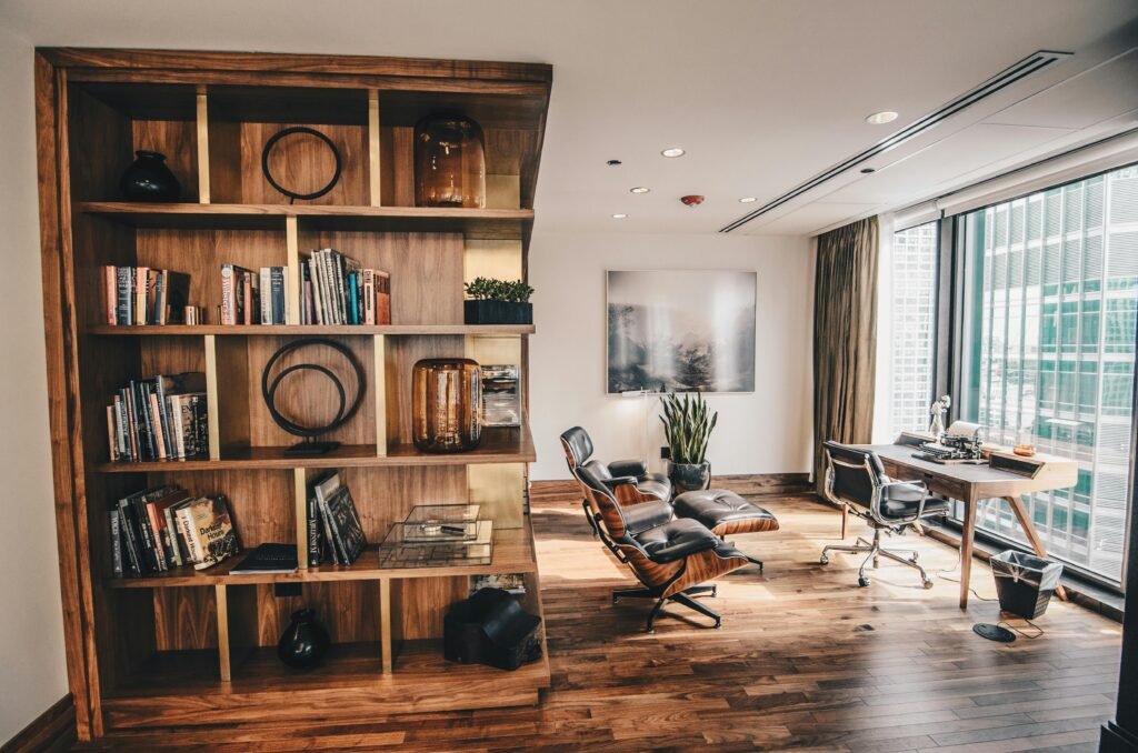 pexels-photo-2883049-2883049 Stylish office space featuring a wooden bookshelf and a minimalist desk setup, ideal for work.