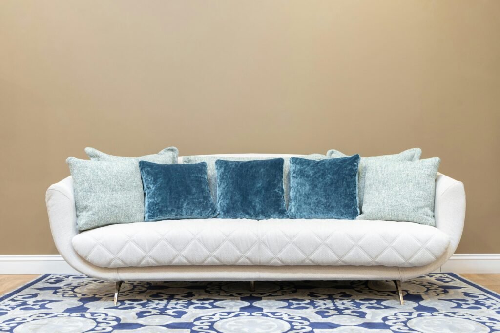 Stylish white sofa with blue throw pillows against a beige wall, perfect for contemporary living.