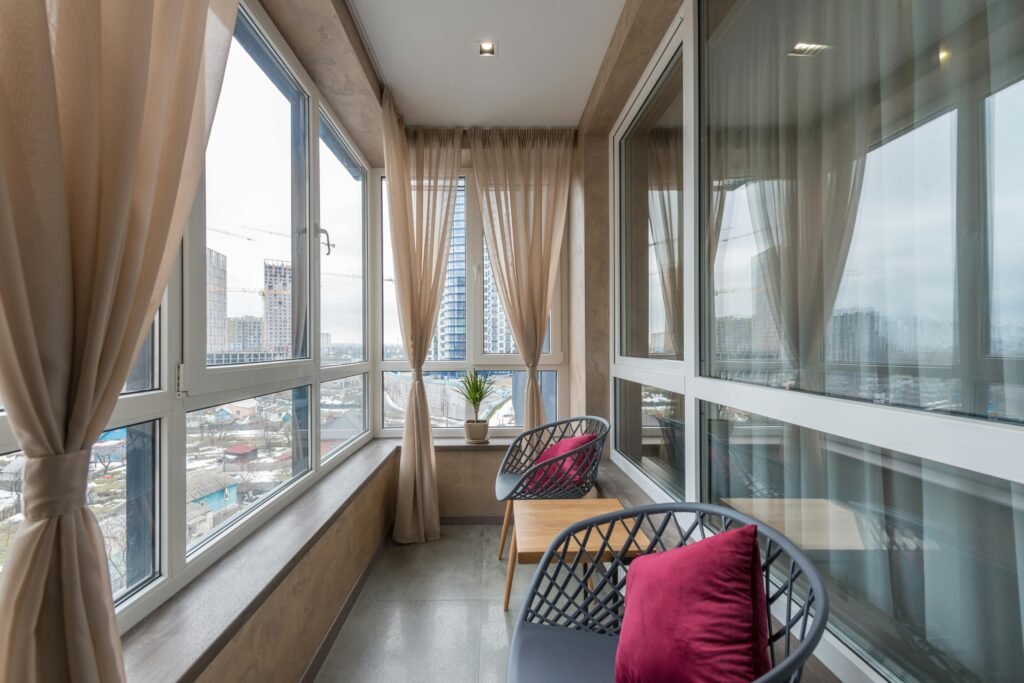 A cozy balcony in a modern apartment with a cityscape view, featuring comfortable chairs and decor.